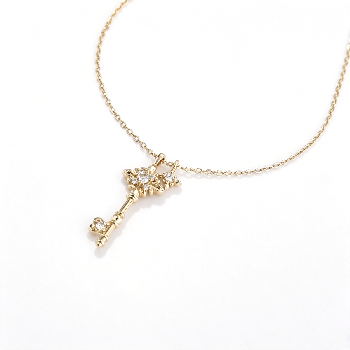 Angled close-up of a gold-tone floral key pendant showing brilliant cubic zirconia details.