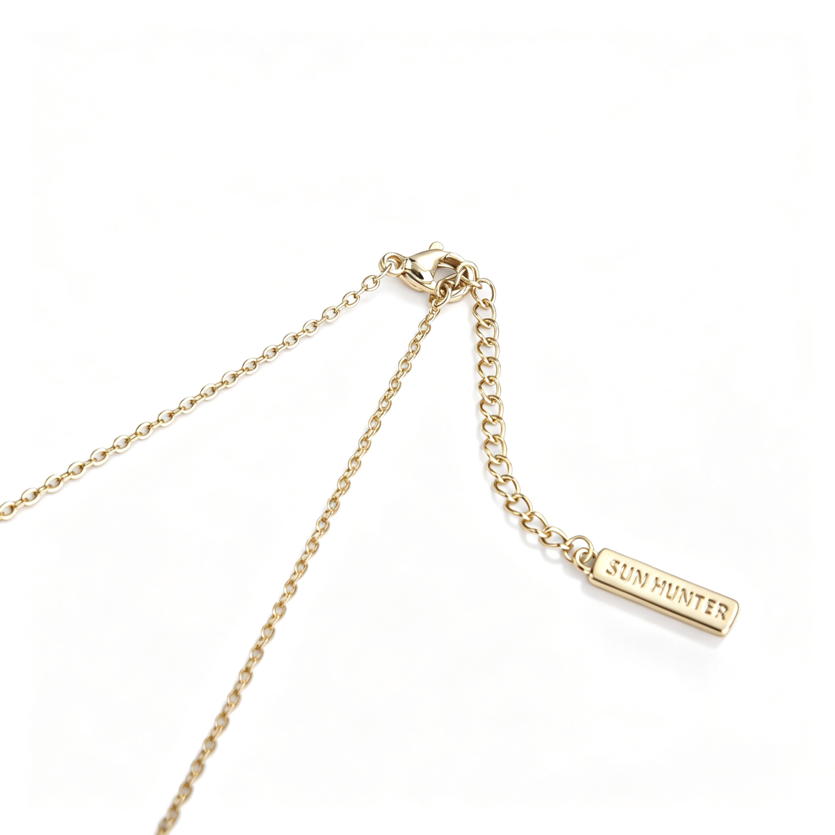 Close-up view of a gold-plated lobster clasp, extender chain, and engraved logo tag.	