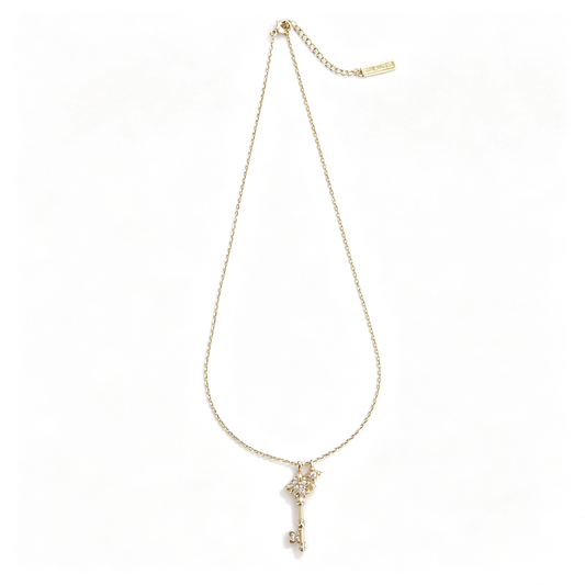 Full view of a gold fleur-de-lis key pendant necklace laid flat on a white background.