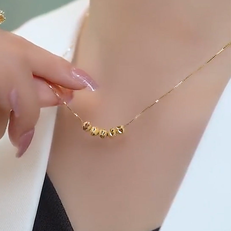 Close-up of the geometric bead necklace worn at the neckline, showing the decorative beads against the skin.