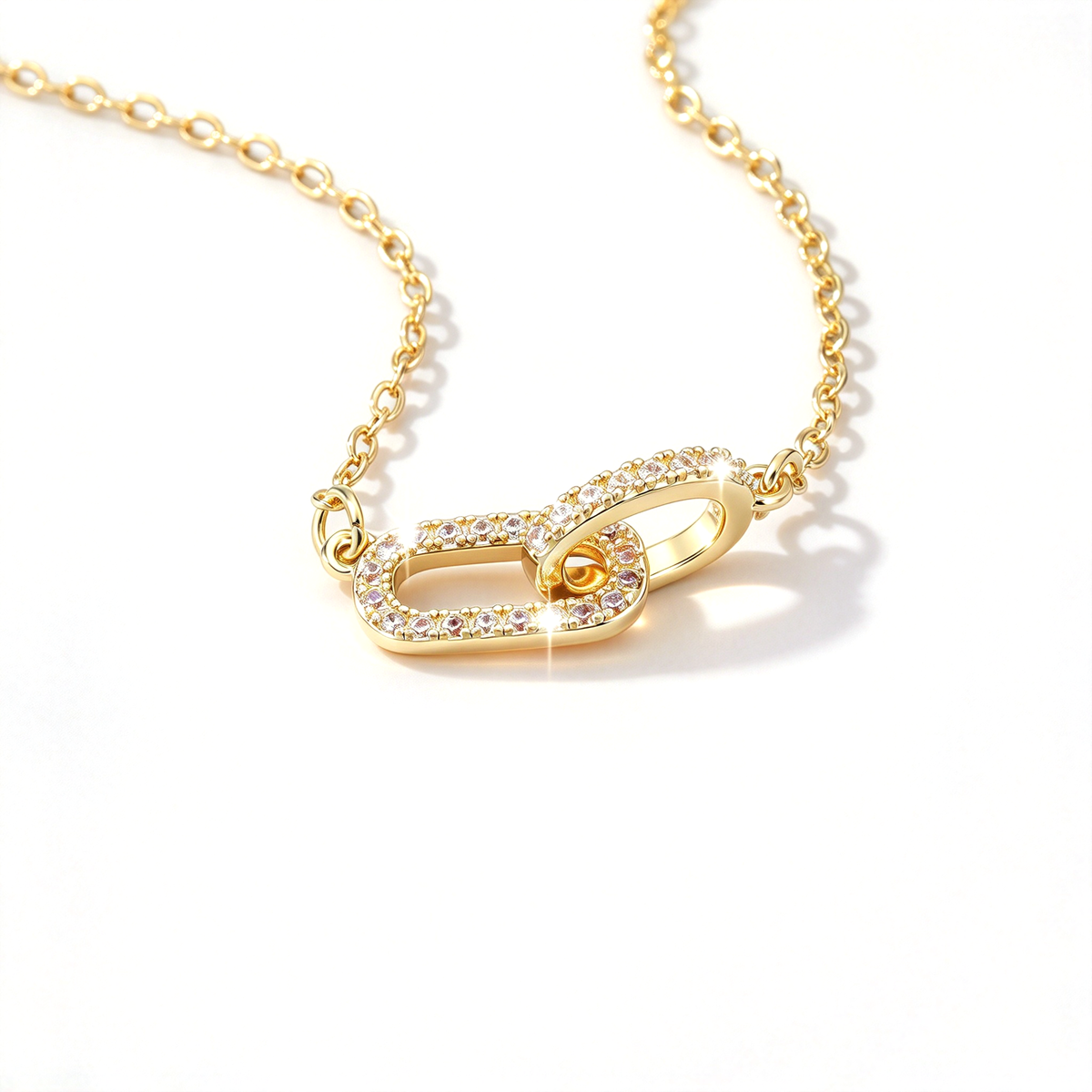 Close-up of a gold-tone geometric link pendant necklace showing its interlocking design and decorative stone details.