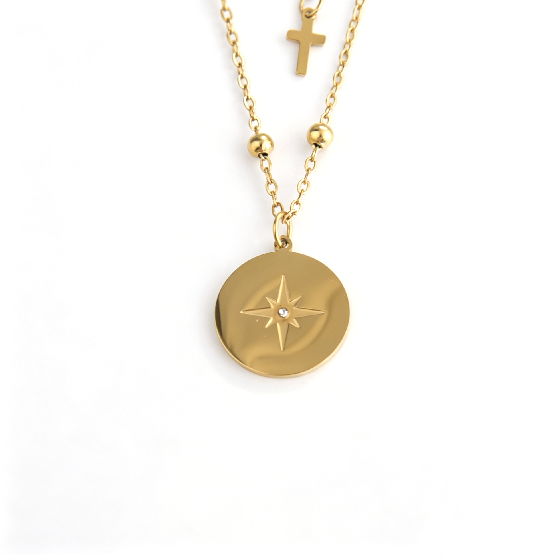 Gold layered cross necklace close-up with zircon starburst coin pendant