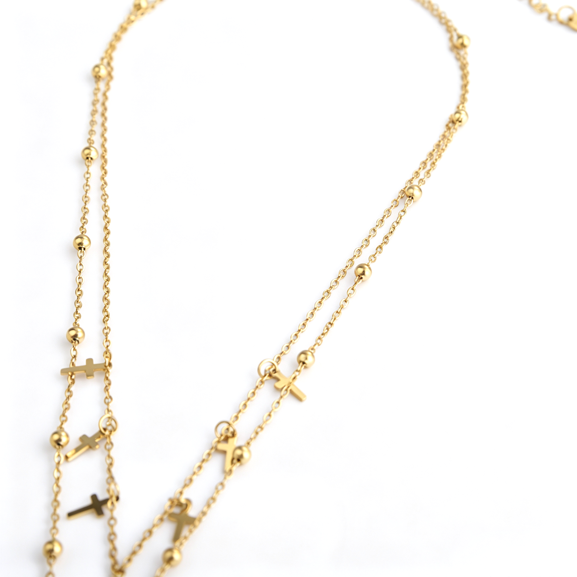 Two gold-tone necklace strands showing spaced beads and cross charms
