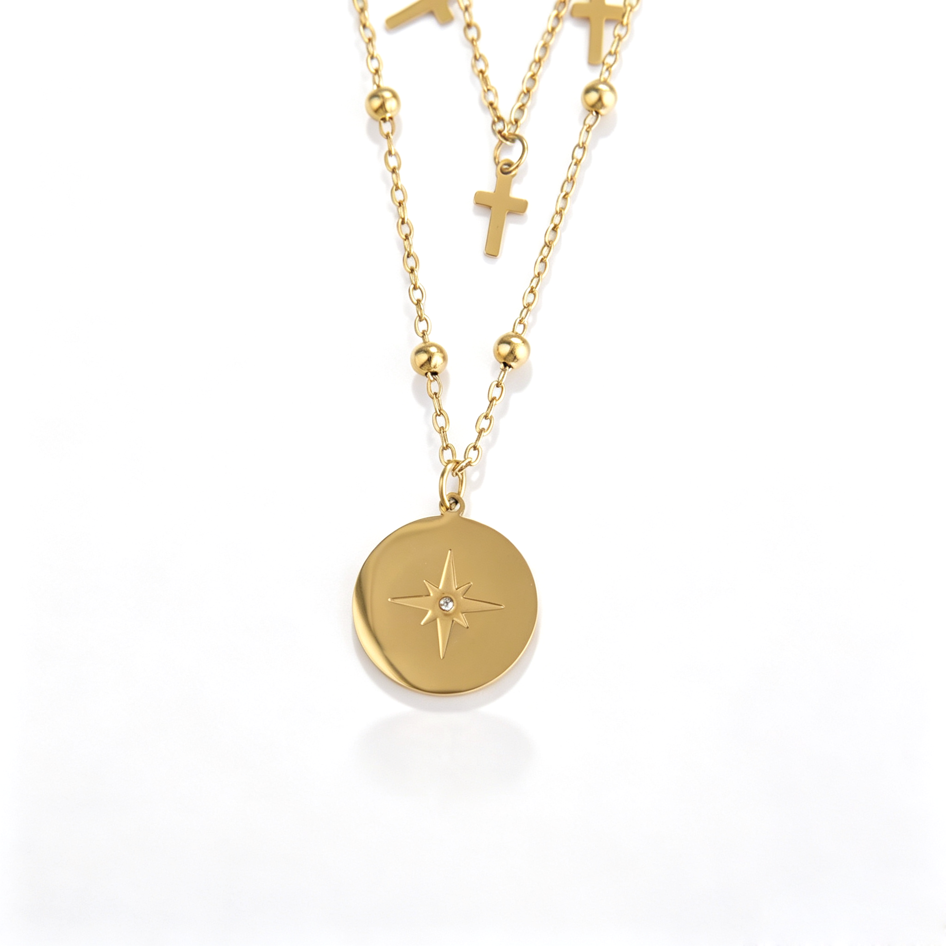 Front detail of zircon-set starburst coin and centered cross pendant