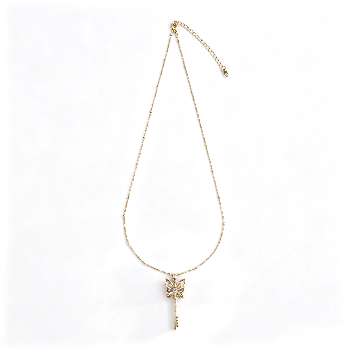 Full view of handcrafted gold butterfly key sweater necklace on white background