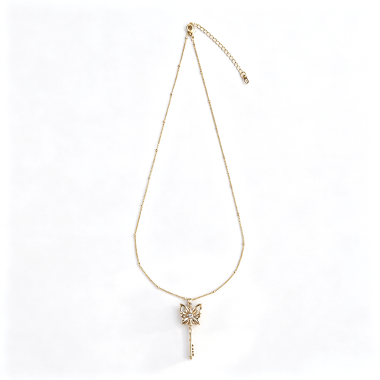 Full view of handcrafted gold butterfly key sweater necklace on white background