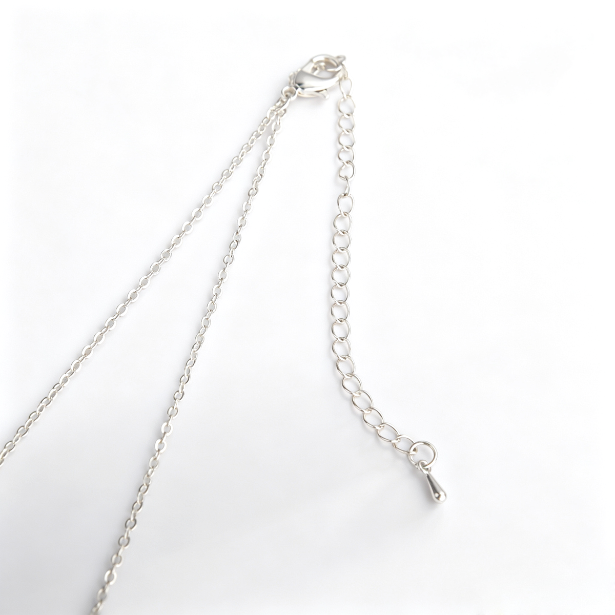 Angled close-up of handcrafted brushed silver alloy geometric pendant showing matte sheen