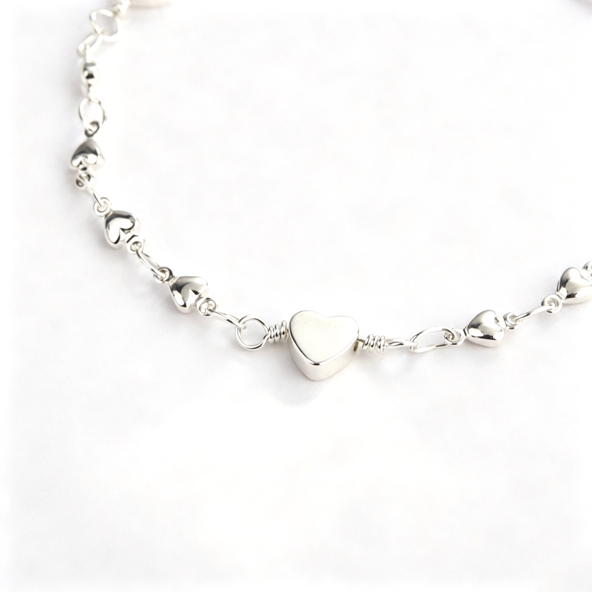 Close-up of the center heart charm and detailed chain links on the bracelet