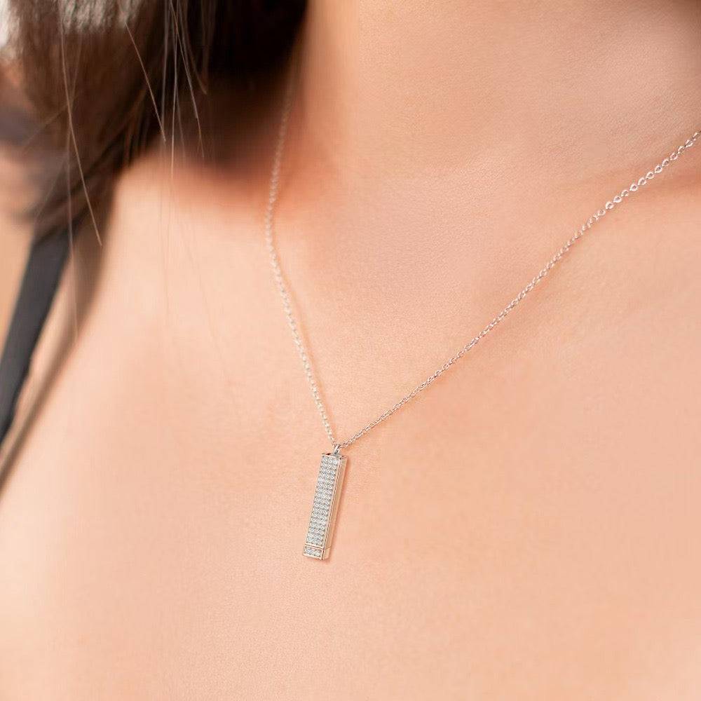 Silver-tone rectangular bar pendant necklace worn against bare skin