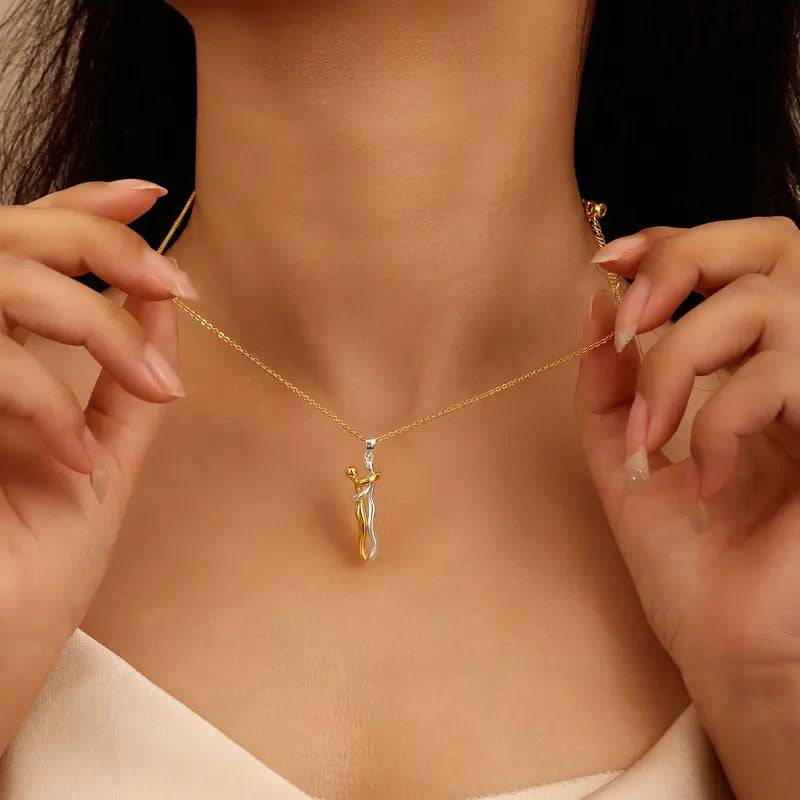 Woman wearing the two-tone hug pendant necklace at the center of an open neckline | 