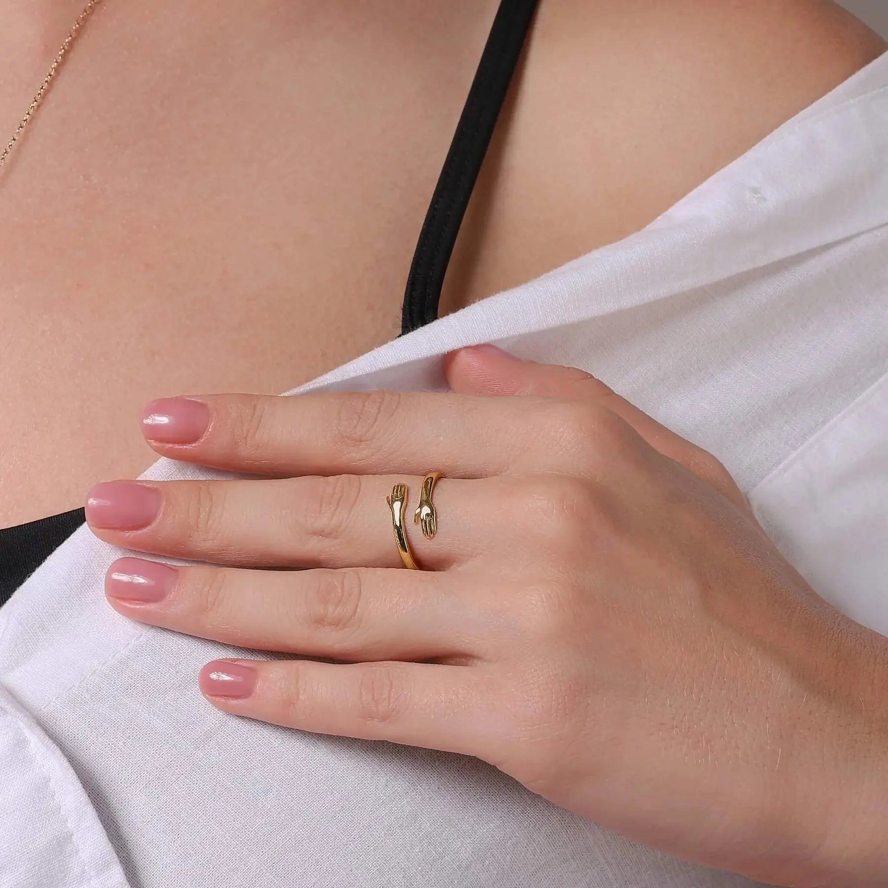 Gold-tone hugging hands adjustable ring worn on a model's hand