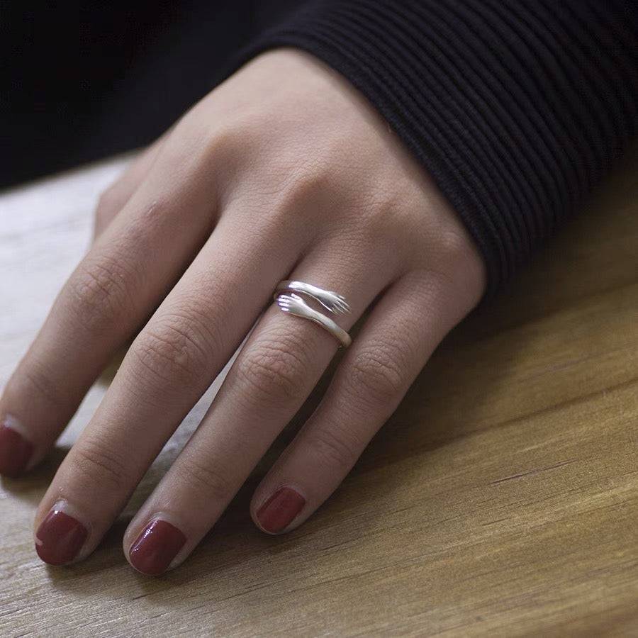 Silver-tone open ring with sculpted hands worn on a finger