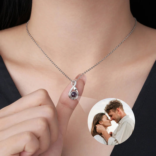 A hand holds the pendant beside a circular photo projection, illustrating its image-viewing feature.