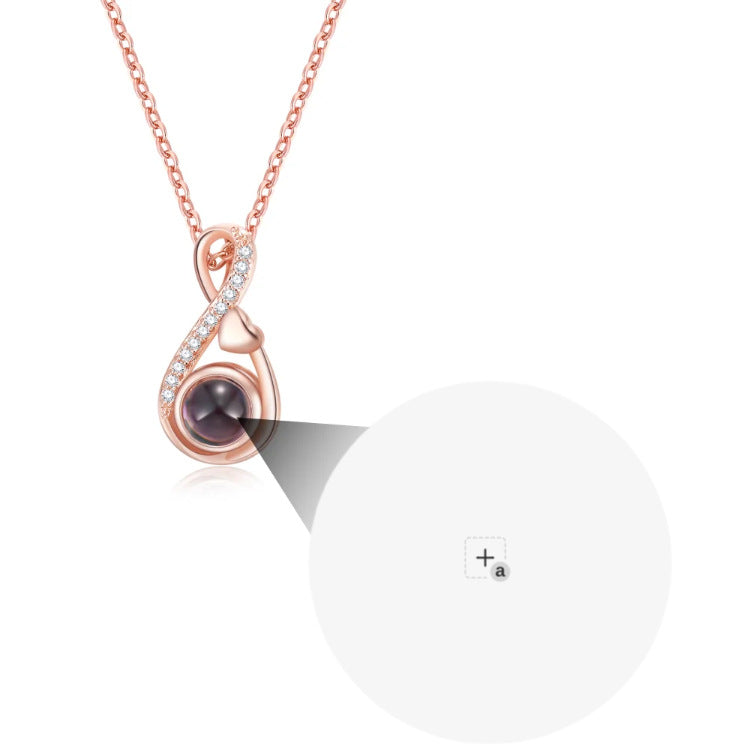 Rose-gold-tone pendant close-up showing the rounded center and curved decorative frame.
