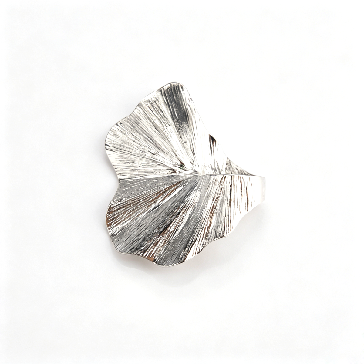 Flat lay view of the silver sculptural leaf ring highlighting the organic fan shape and ridges.