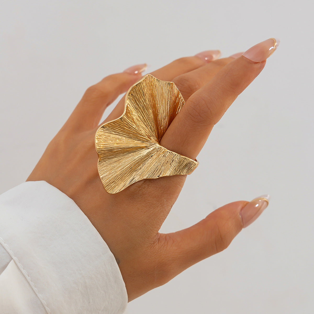 Model wearing the oversized 18k gold-plated ginkgo leaf ring paired with a white button-down shirt.