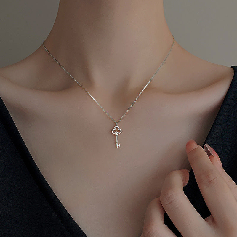 Key charm necklace shown at the neckline against a dark top for a subtle everyday look