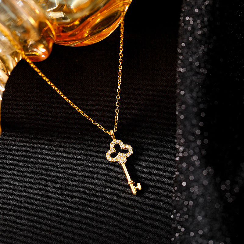 Close-up of a key-shaped pendant with a decorative top resting against a dark textured background