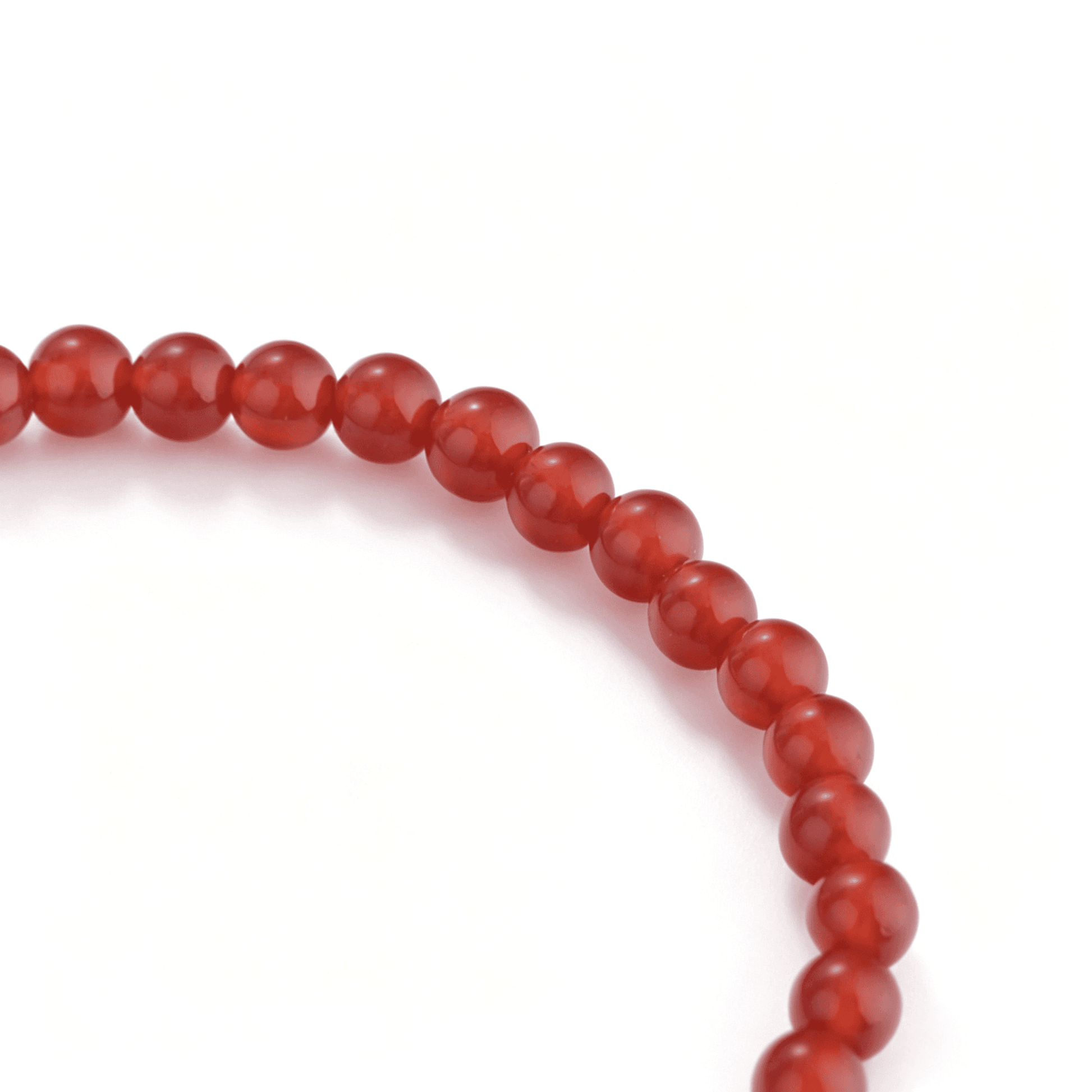 Macro detail of the glossy translucent red agate beads arranged on the elastic stretch bracelet.