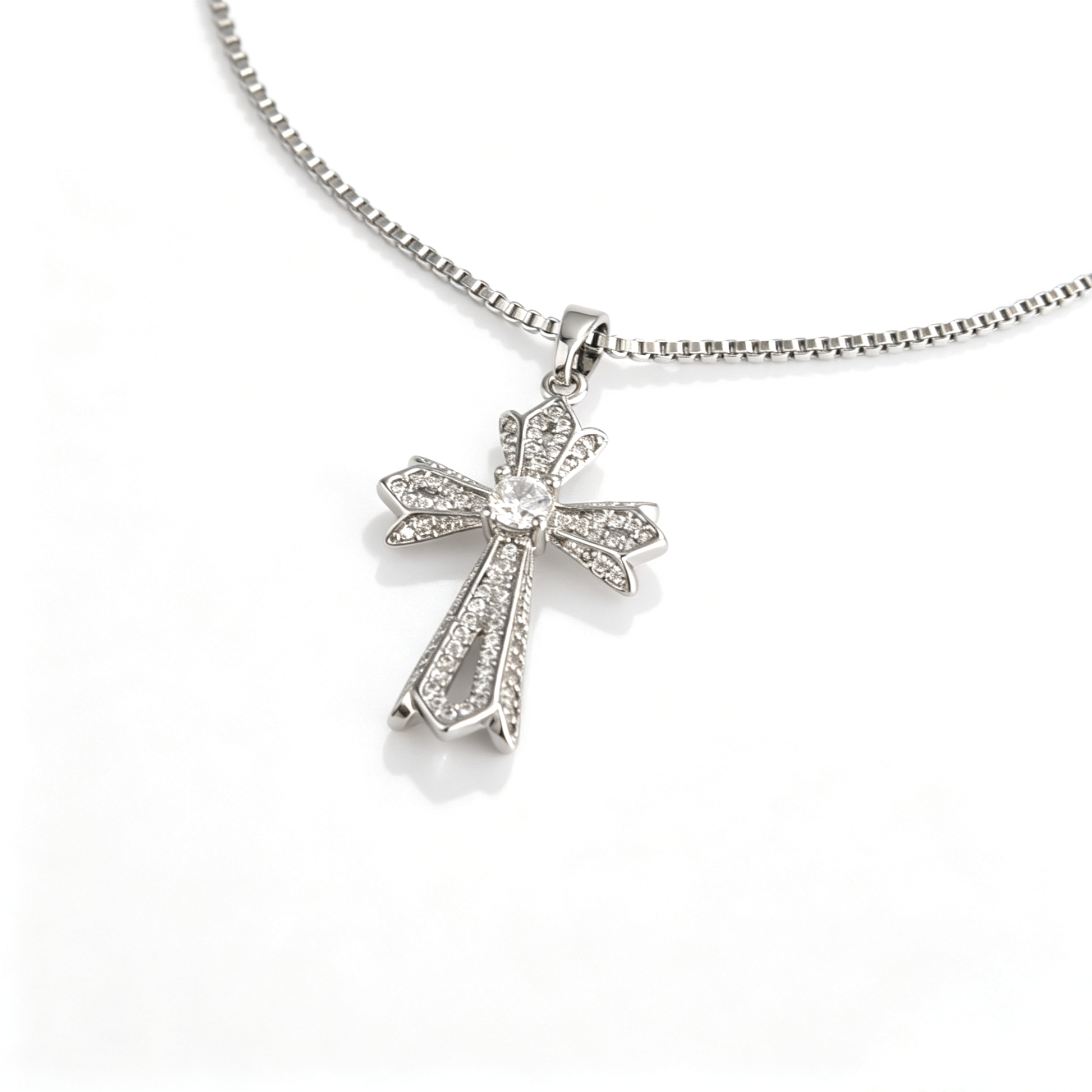 Angled close-up showing the layered cross pendant's raised openwork profile and center accent.