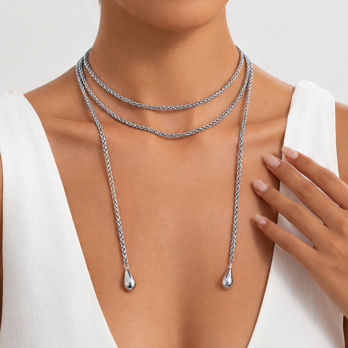Silver-tone necklace worn with a white V-neck top, highlighting the contrast between the chain and the neckline