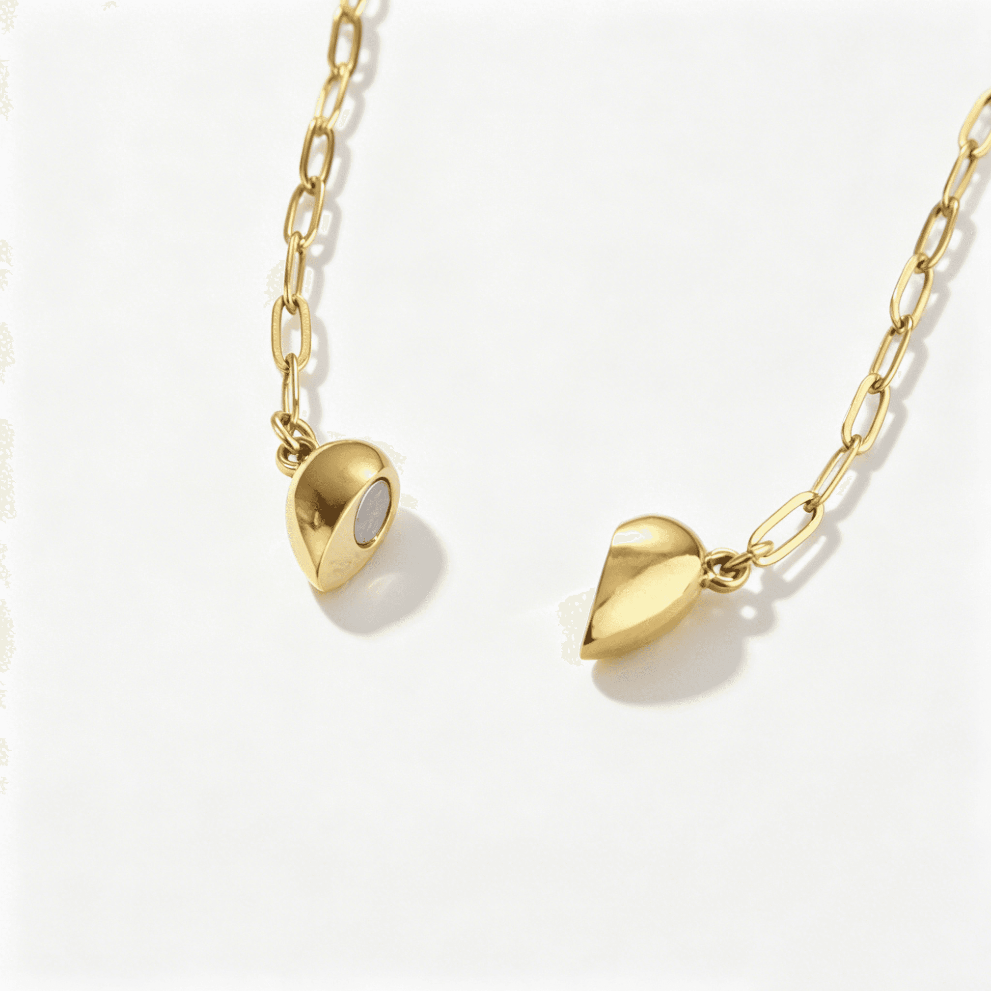 A close-up view showing the internal magnets of the separating gold heart pendants for a matching necklace set for couples.