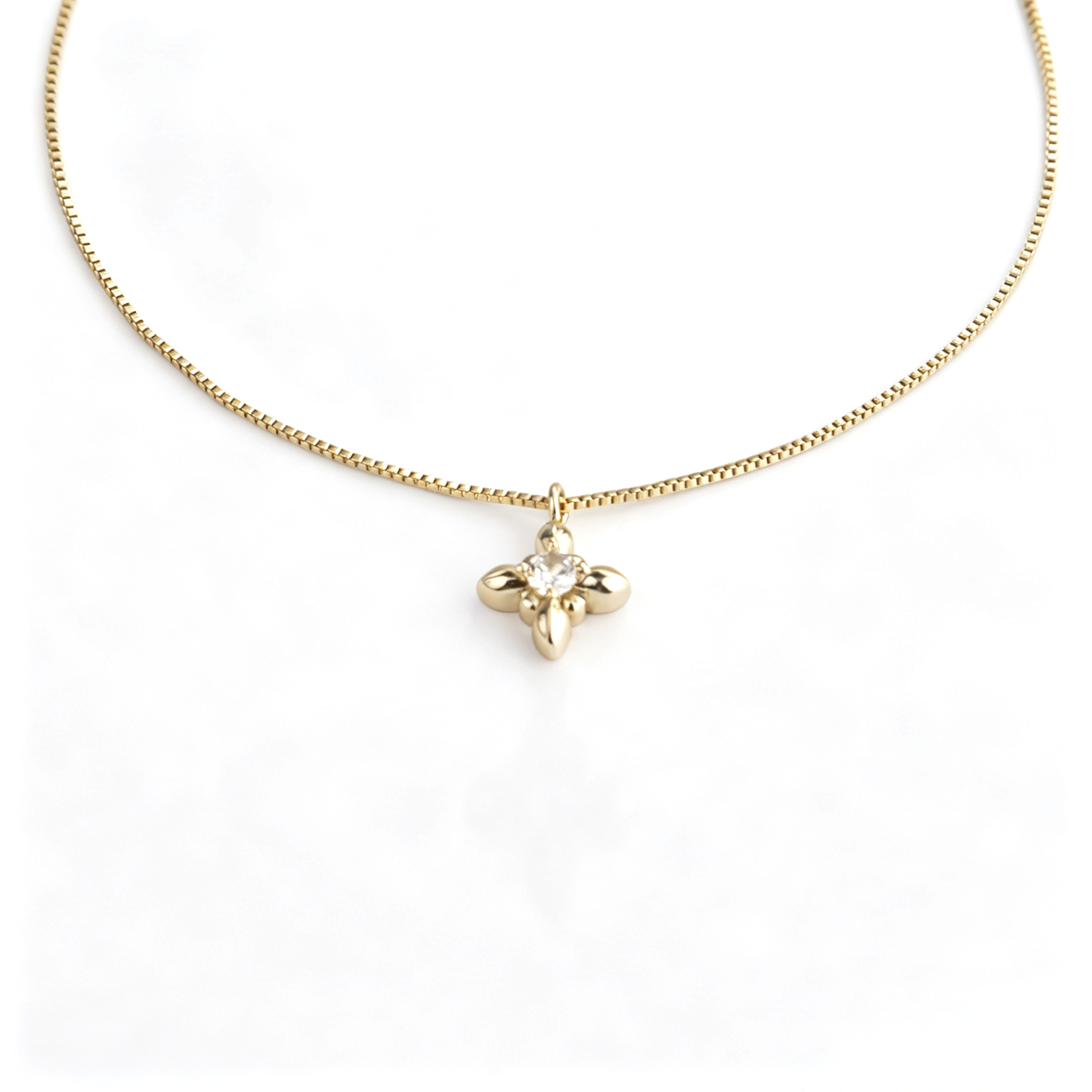 Close front view of a gold flower pendant necklace with a mini iris charm on a box chain.