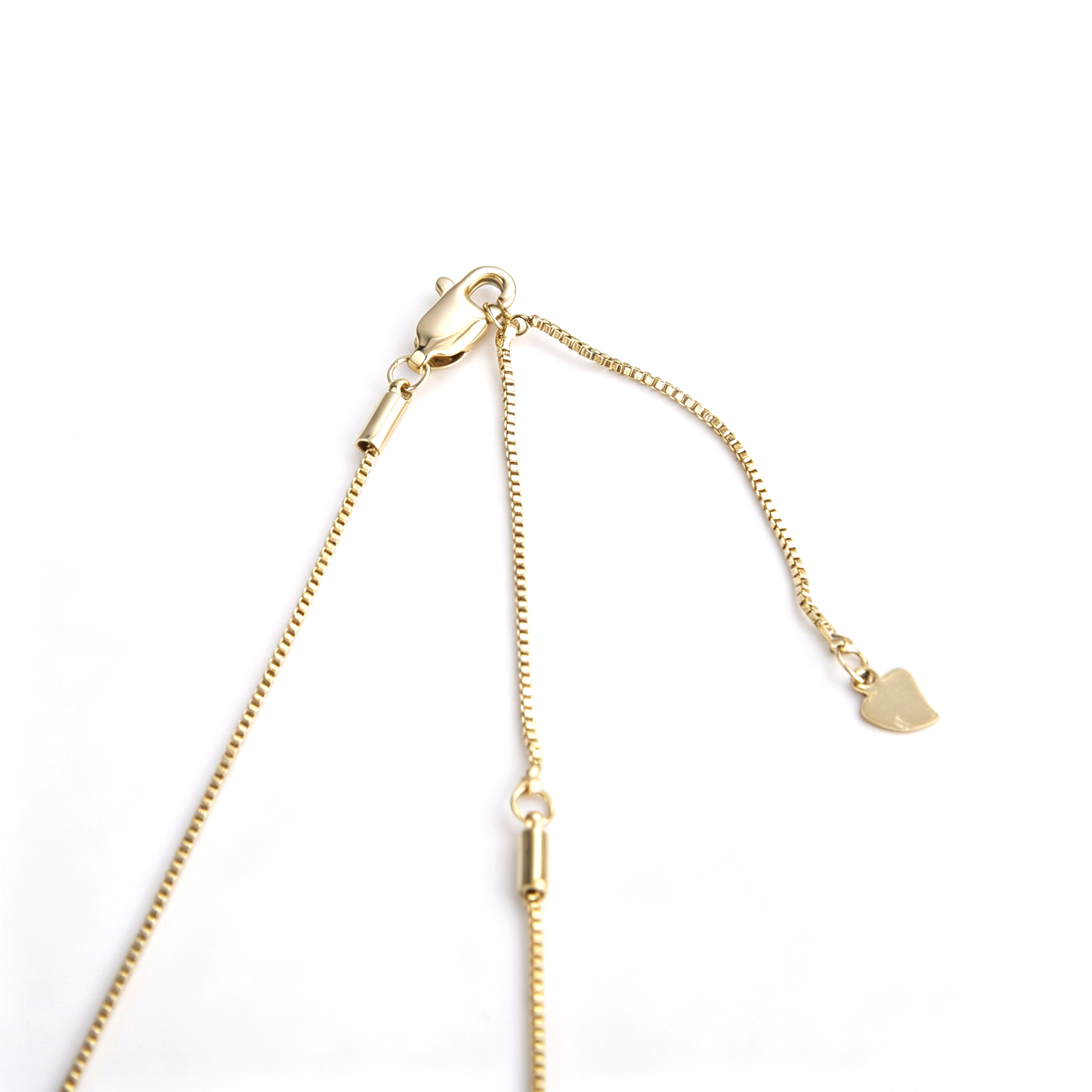 Lobster clasp, adjustable chain ends, and small heart-shaped end tag on the gold box-chain necklace.