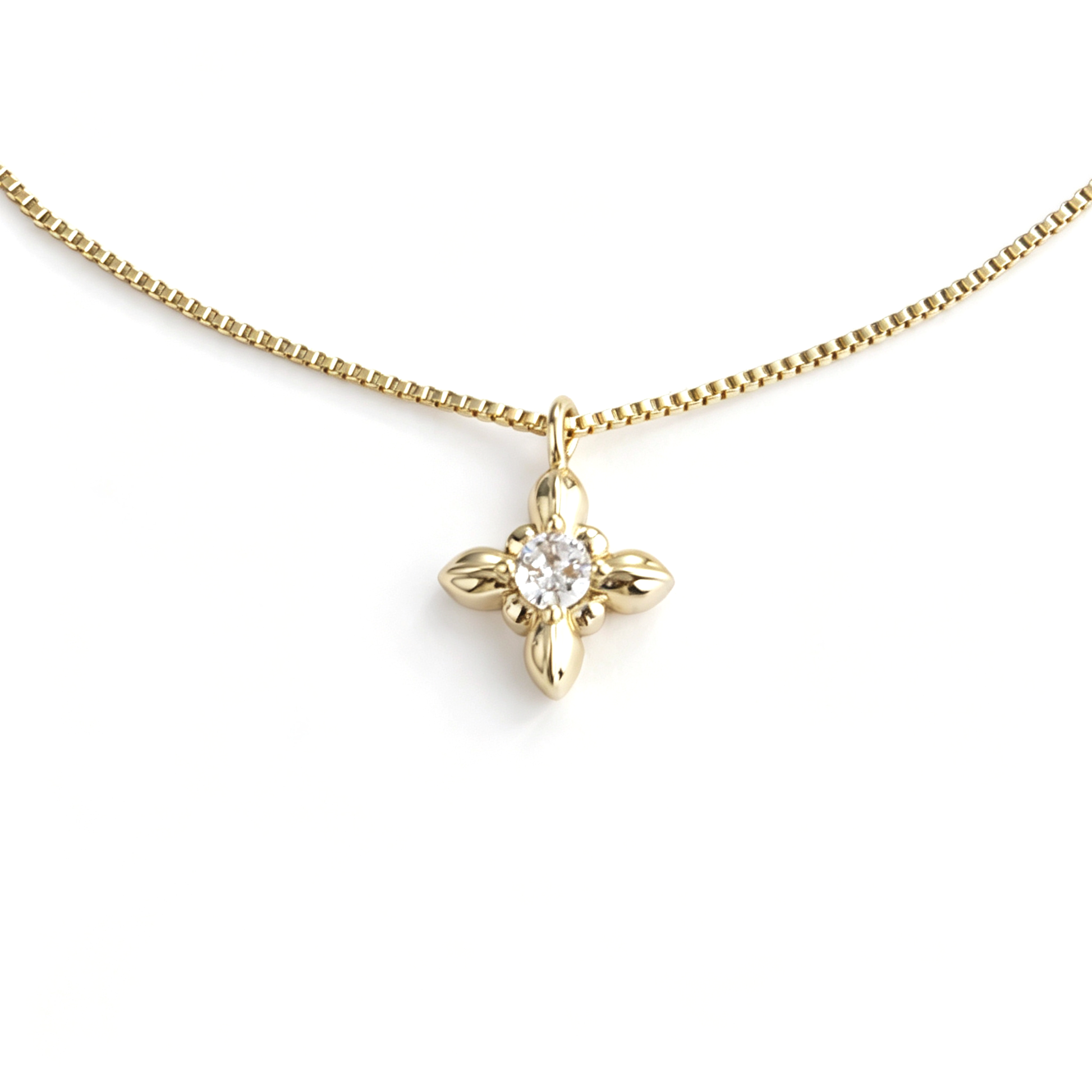 Macro view of the iris pendant with a round clear zircon center and polished gold-tone petals.