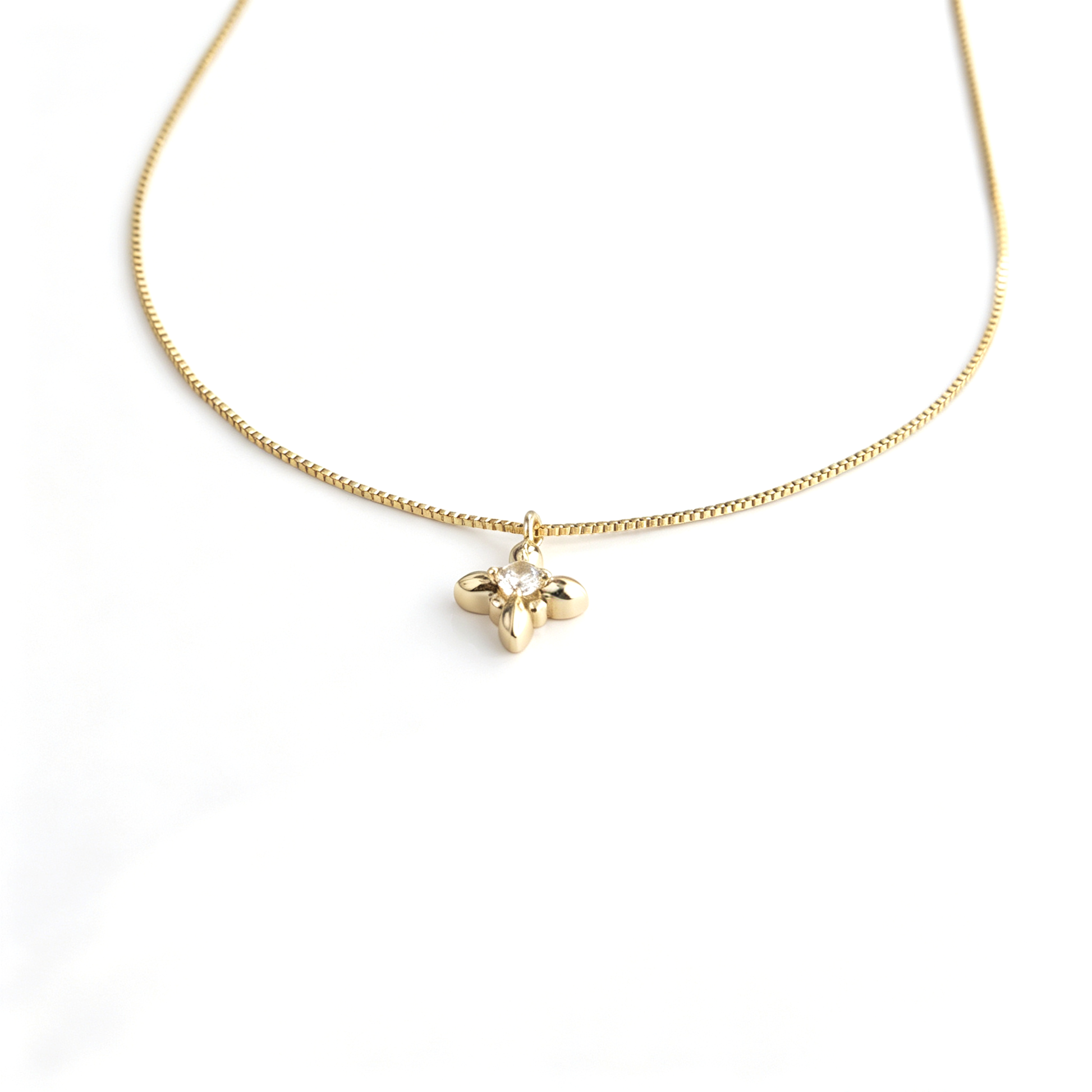 Centered front view of the mini iris flower pendant suspended from a fine gold box chain.