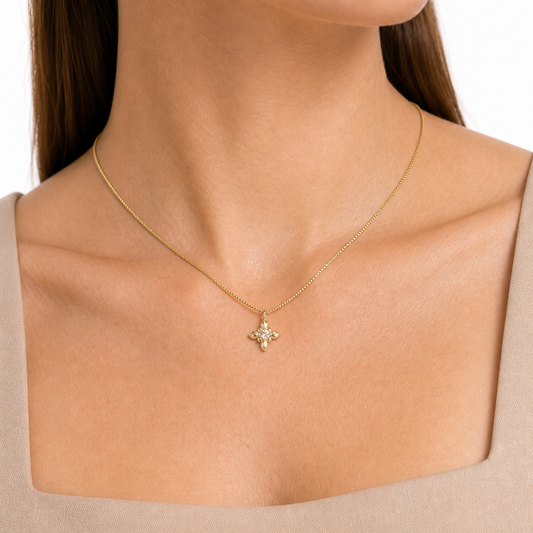 Close-up of a miniature iris pendant with zircon center and fine gold box chain at the collarbone.