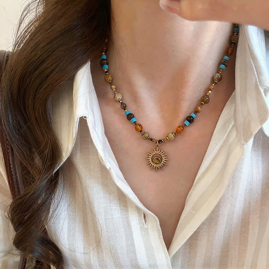 Multicolor beaded sun necklace worn at the collarbone with an open white shirt, showing how the pendant sits when styled.