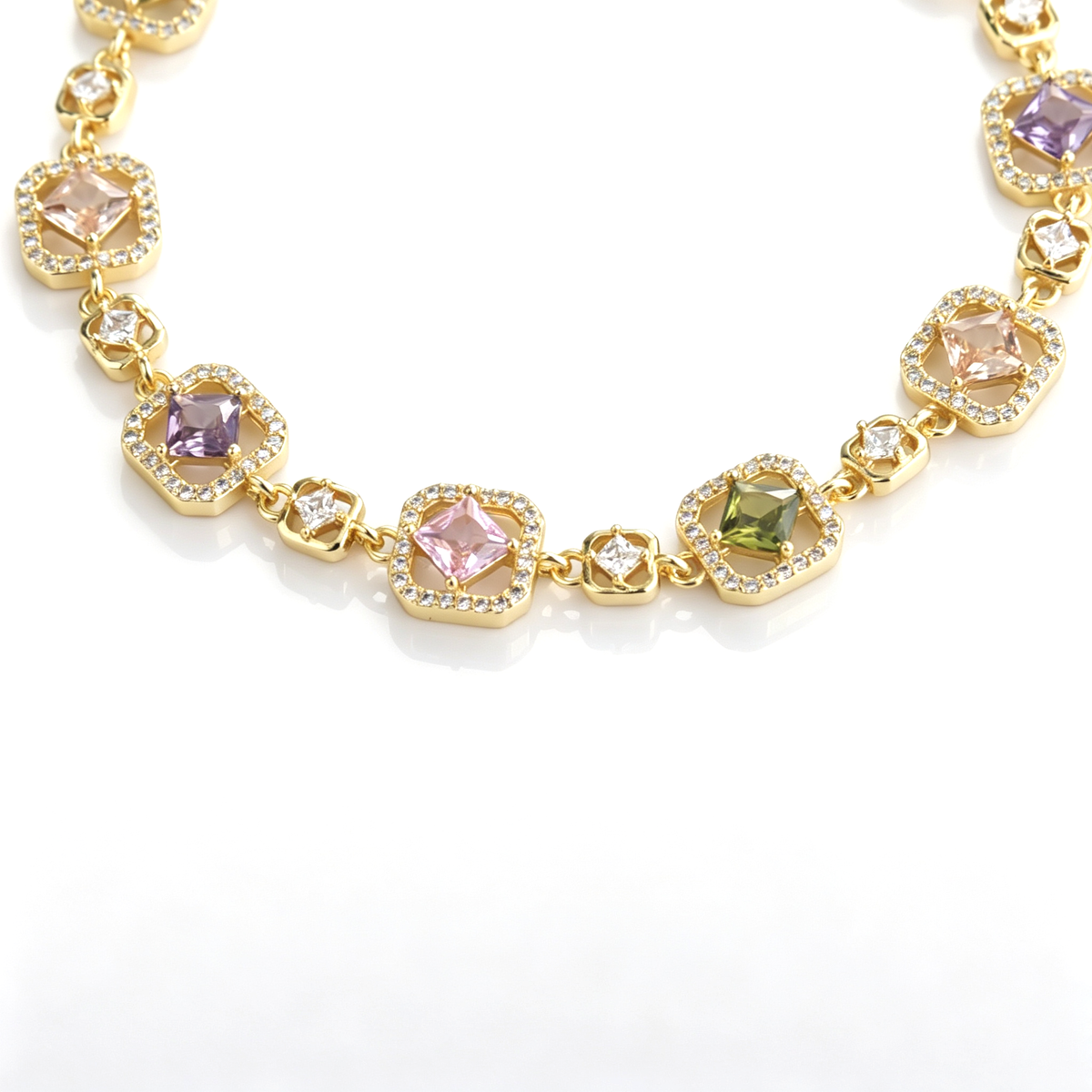 Detailed view of gold-tone bracelet links with pastel cushion-cut cubic zirconia and pavé halos.