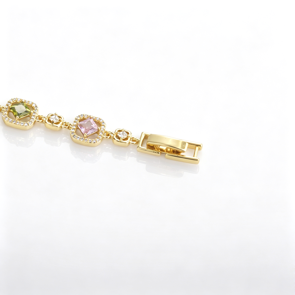 Side angle of a gold-plated link bracelet highlighting the fold-over clasp and green CZ stone link.