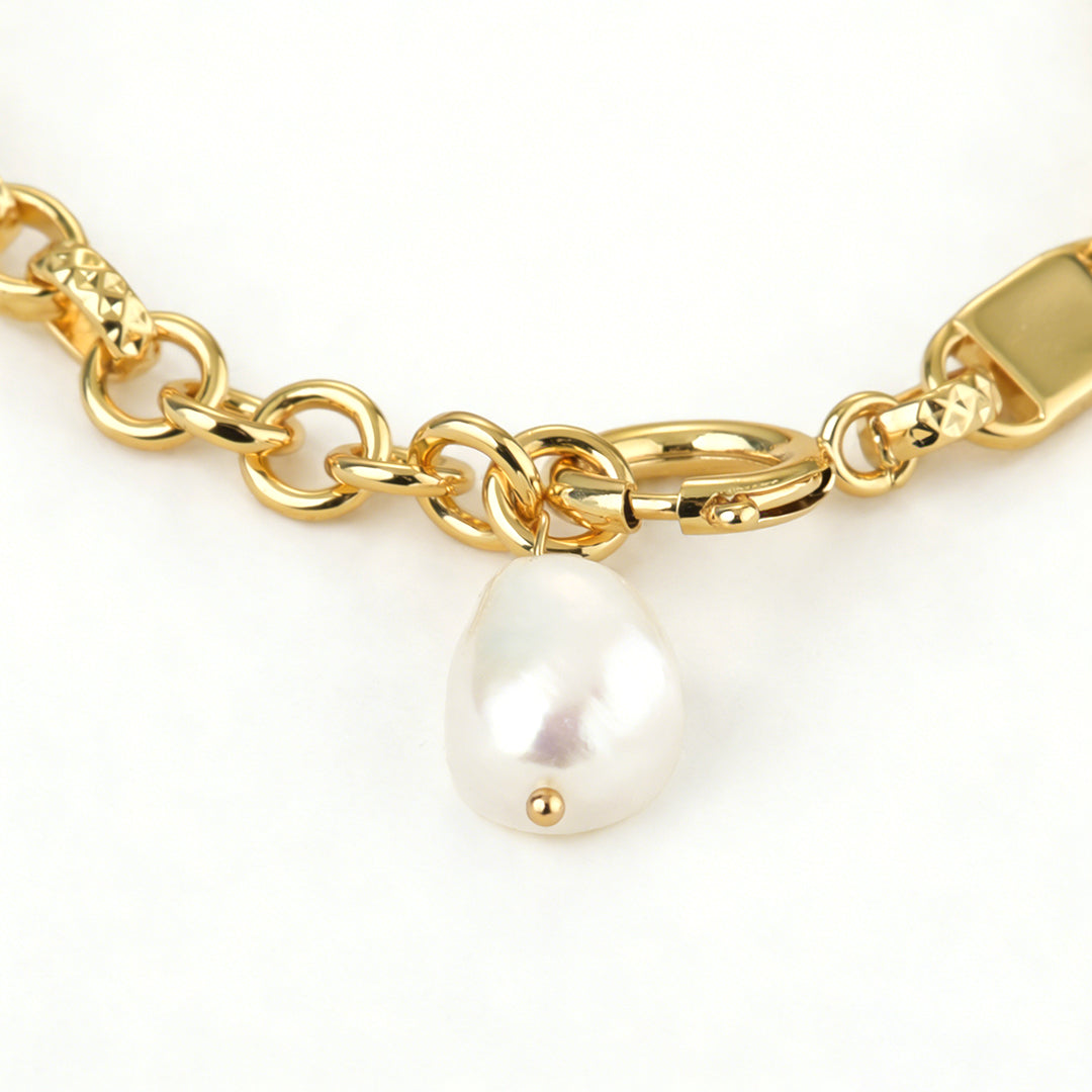 Close-up of a genuine iridescent baroque pearl charm on a gold link bracelet.