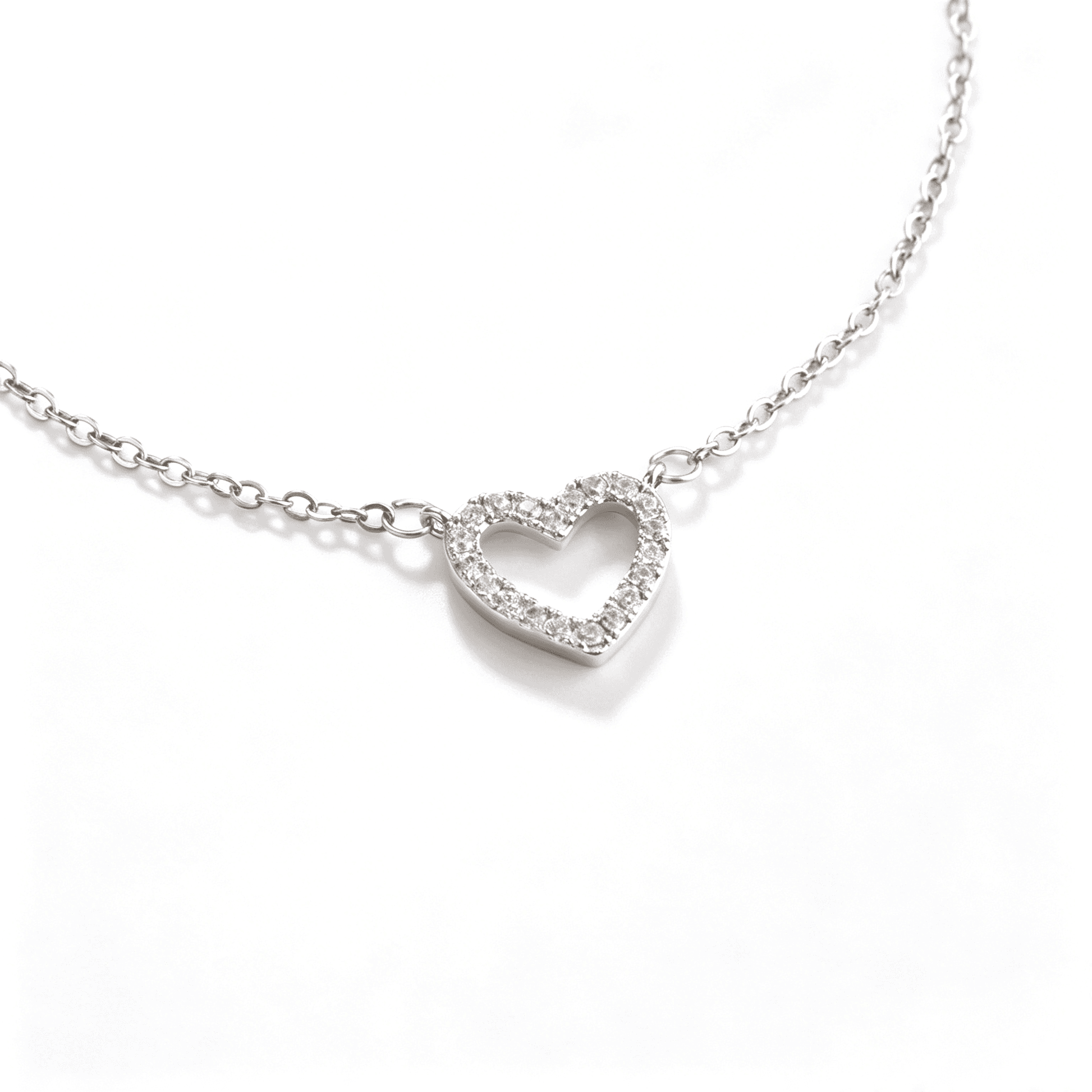Angled close-up of a silver-tone open heart pendant set with clear cubic zirconia