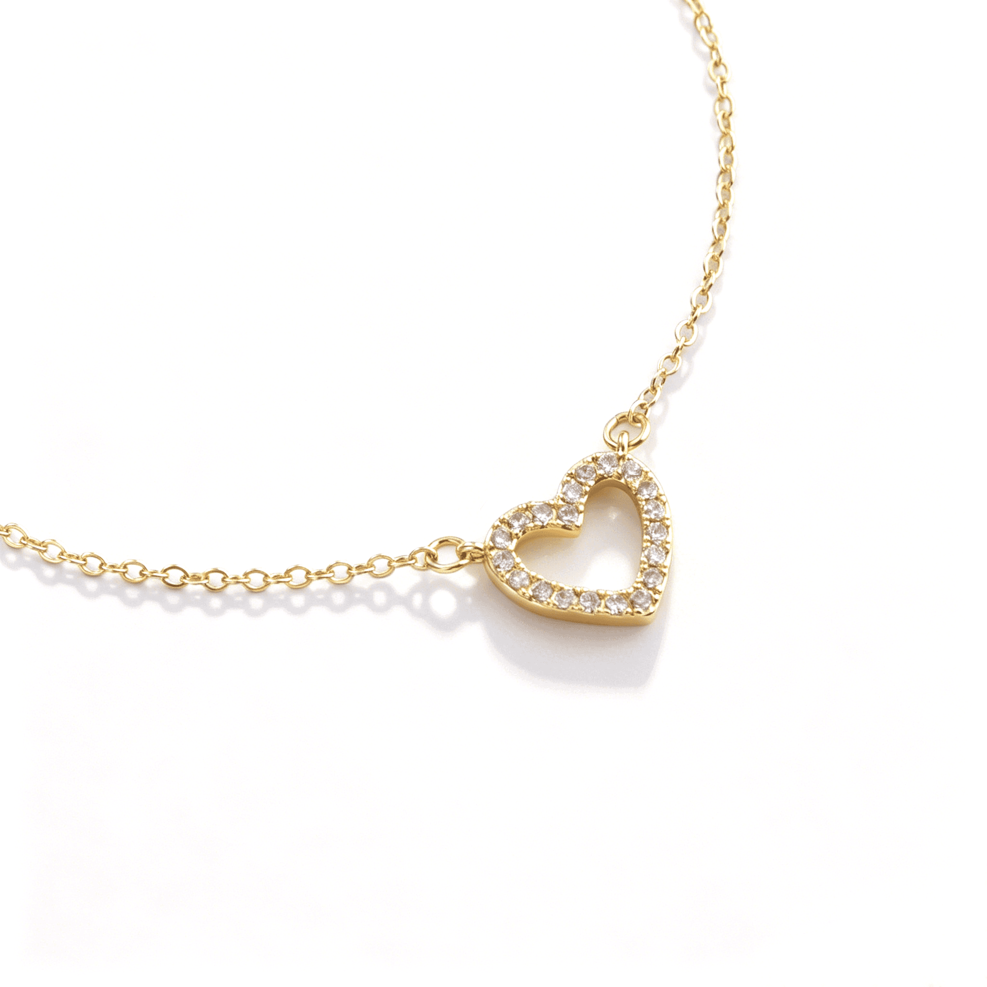 Angled close-up of a gold-tone open heart pendant and clear stones