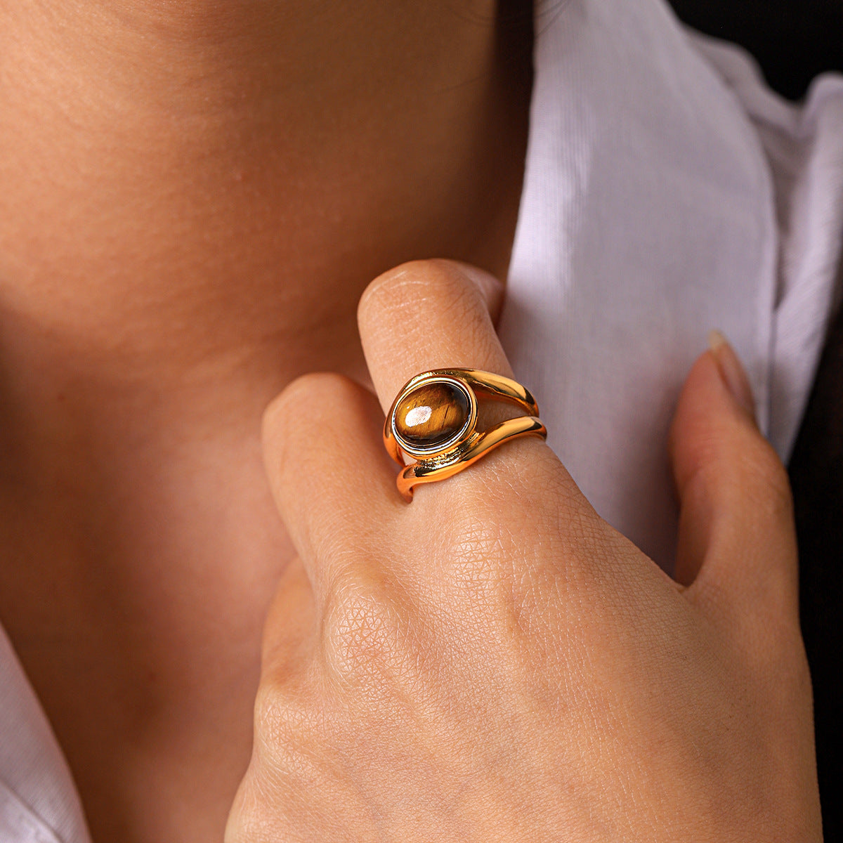 A close-up of the oval centerpiece ring worn on a finger, showing its raised design.