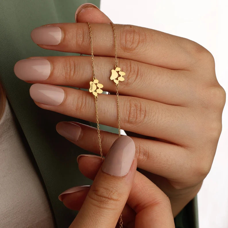 Close-up of paw-shaped bracelet charms held between fingers for a detailed view.