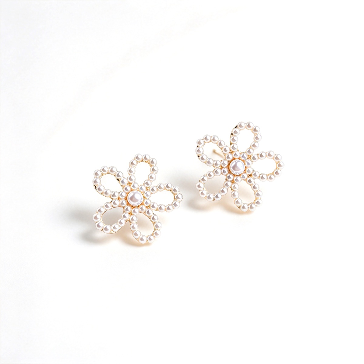 Pair of flower stud earrings arranged diagonally to show their shape and decorative centers.