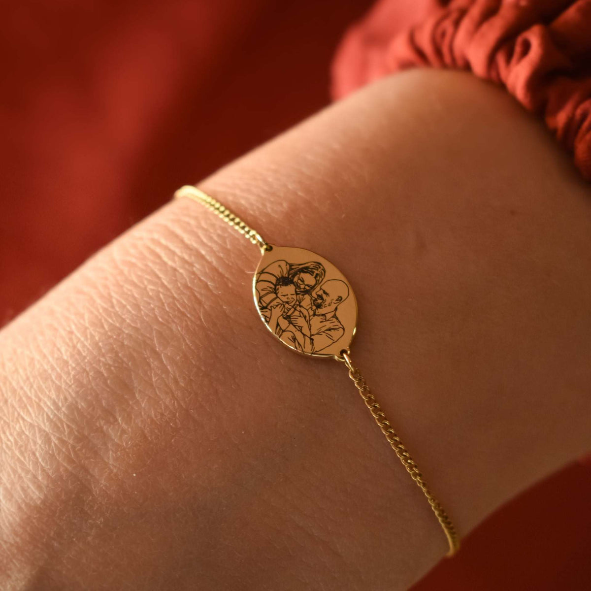Personalized engraved family bracelet worn on wrist showing a custom family portrait design on the oval charm