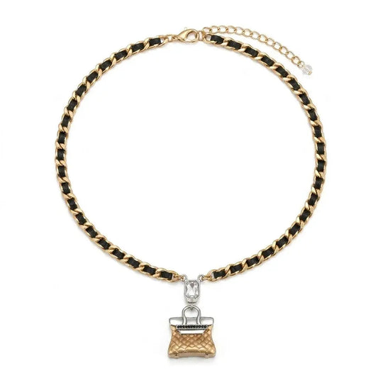 Close-up of Ever P. vintage quilted handbag pendant necklace in two-tone gold and silver, draped over a brown ceramic fan prop.
