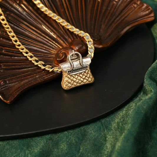 Detailed view of the 18k gold plated quilted bag charm necklace showing the black leather-interwoven chain and clear crystal connector.