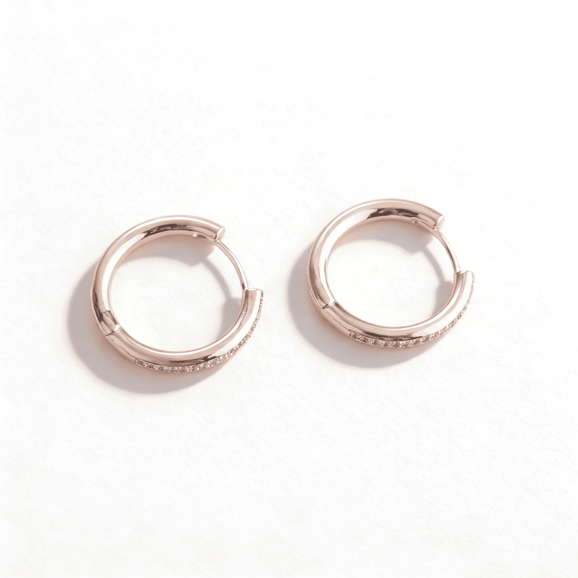 Comparison of rose gold and silver plated hoop earrings with full-circle zirconia crystals.