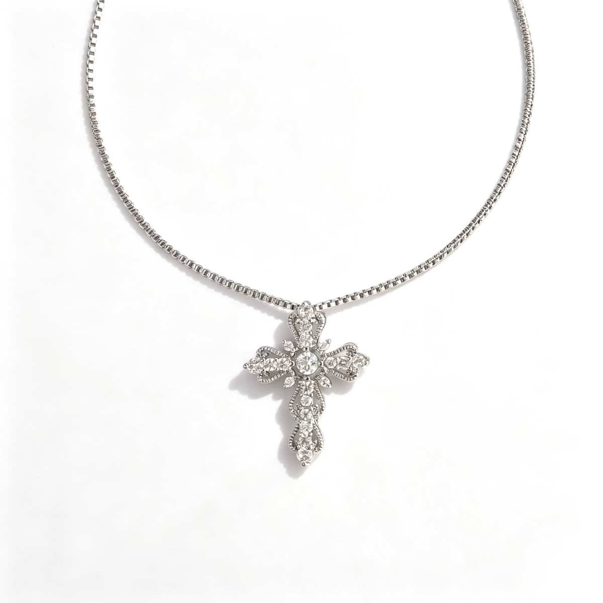 Front view of a scalloped cross pendant set with a central crystal and pavé cubic zirconia.