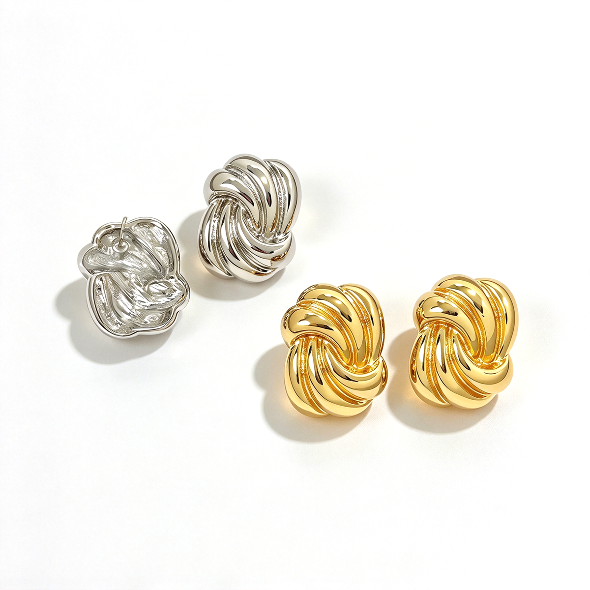 Sculptural knot stud earrings displayed in gold-tone and silver-tone color options.