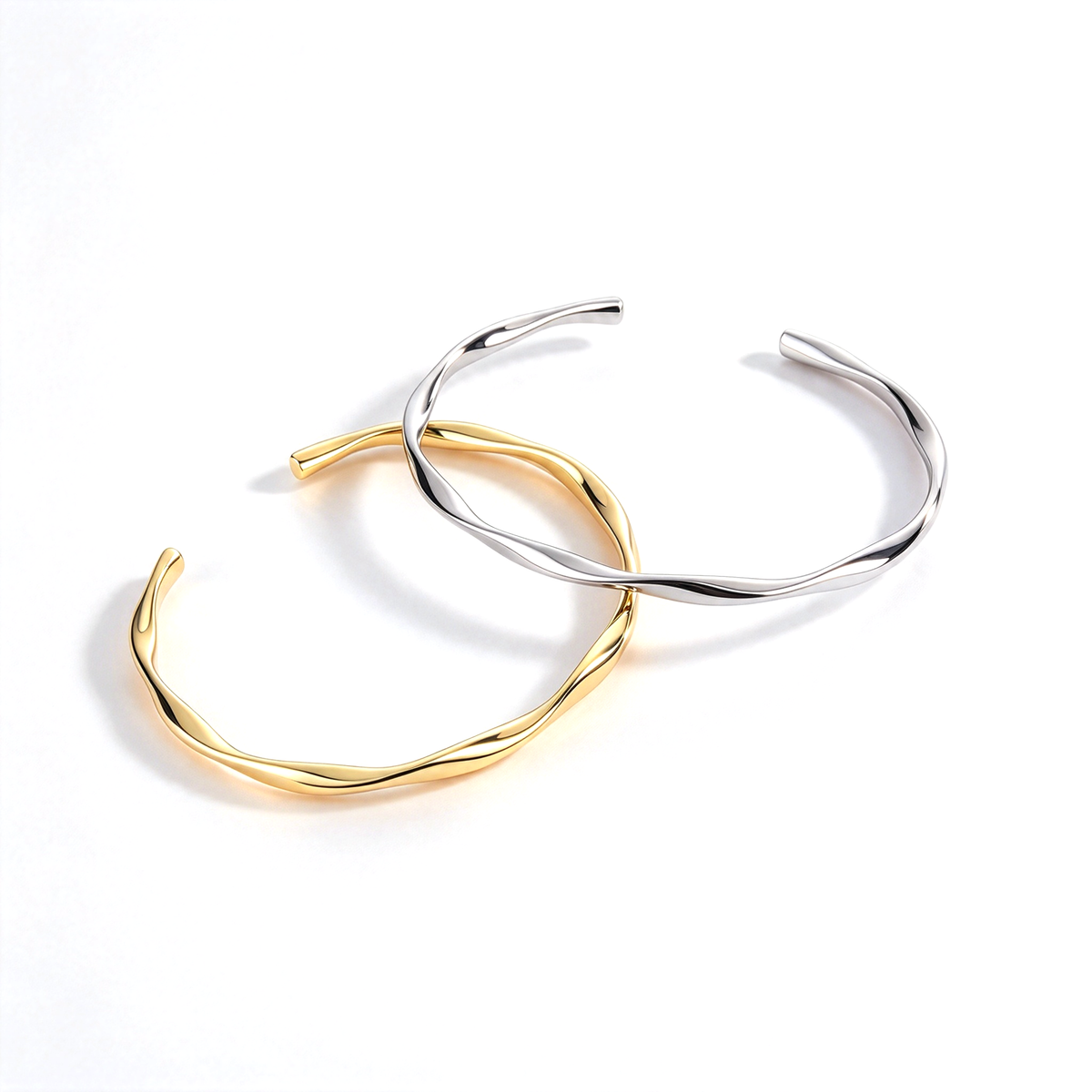 Gold and silver tone open cuff bracelets arranged in an overlapping display