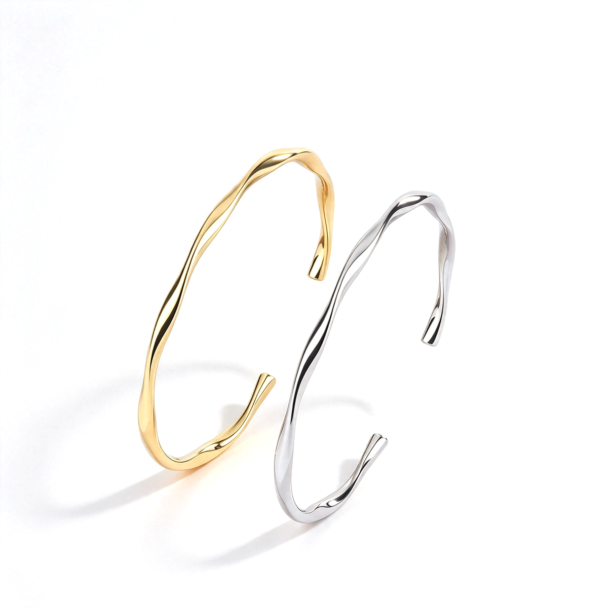 Gold and silver tone cuff bracelets displayed upright to show their curved profiles