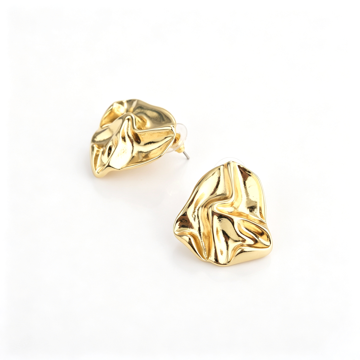 Angled view of gold-tone crumpled metal stud earrings on white background