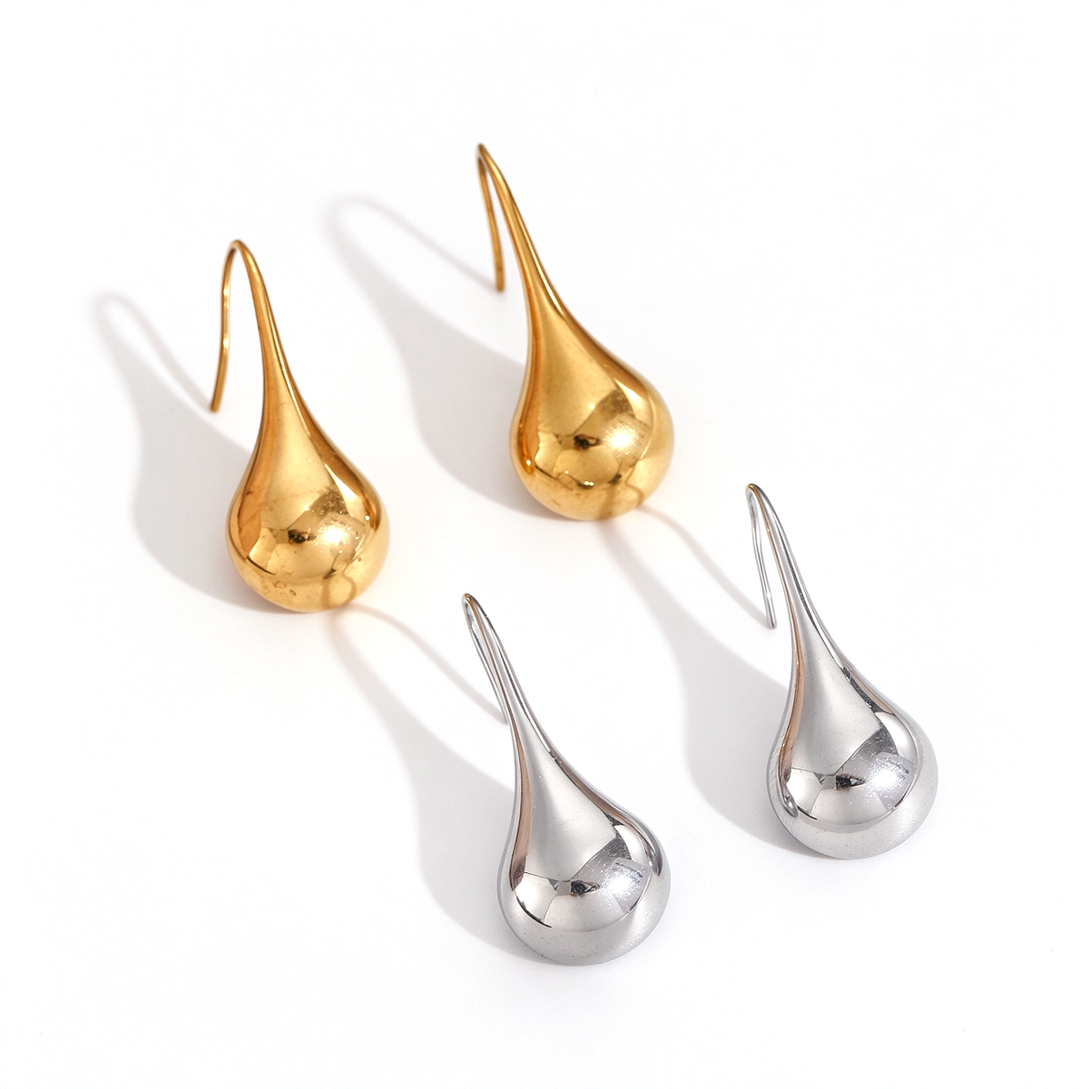 Sculptural teardrop dangle earrings in gold-tone and silver-tone, displayed on a white background.
